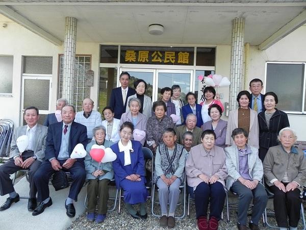 桑原公民館の前で年配の方がみんなで写真をとっている写真