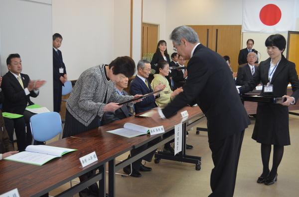 年配の女性が賞状を受け取り頭をさげている写真
