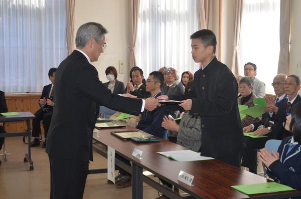 角刈りの学ラン姿の男子学生が立ち上がり賞状を受け取っている写真