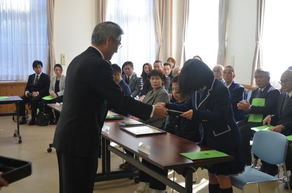 制服姿の女子学生が頭をさげ賞状を受け取っている写真