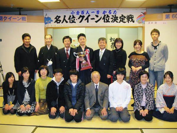 かるた大会で初防衛の岸田 諭名人がトロフィーを持って篠山かるた協会の皆さんと一緒に記念撮影している写真