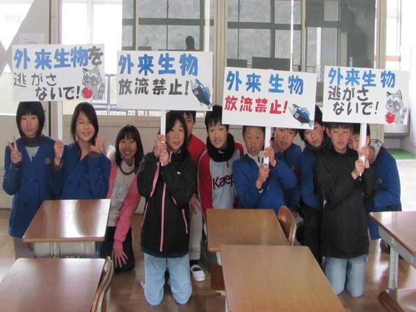 外来生物を逃がさないで、放流禁止のプラカード4枚を持った小学生の写真