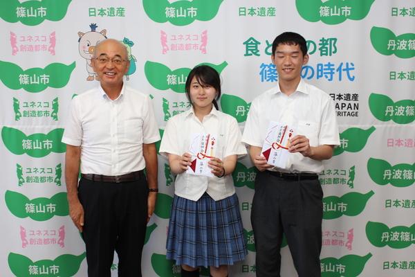 全国大会へ出場する谷田 悠奈さんと中野 一貴さんが奨励金を持ち、市長と記念撮影