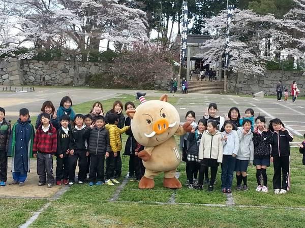 桜が咲いている篠山城跡にてゆるキャラを真ん中に子供や母親たちと一緒に記念撮影している写真