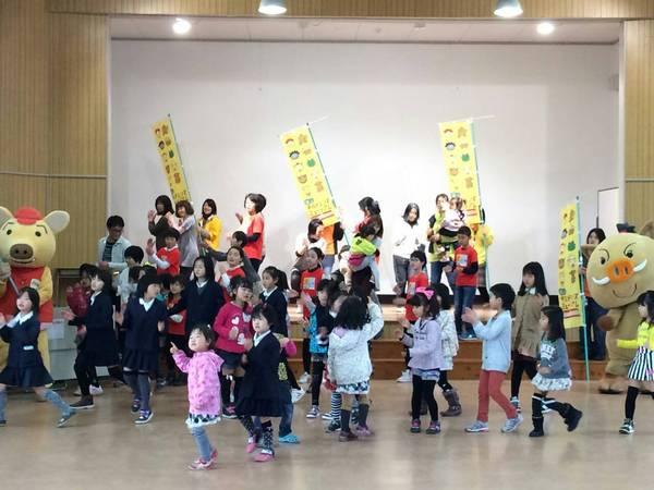 子供と大人が両手を右ほほに持っていき楽しく踊っている写真