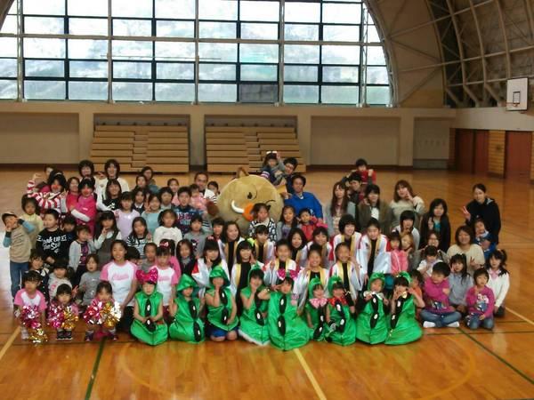 篠山市立川代体育館の中で色々な衣装を着ている子供達や大人が揃ってマスコット人形と一緒に記念写真