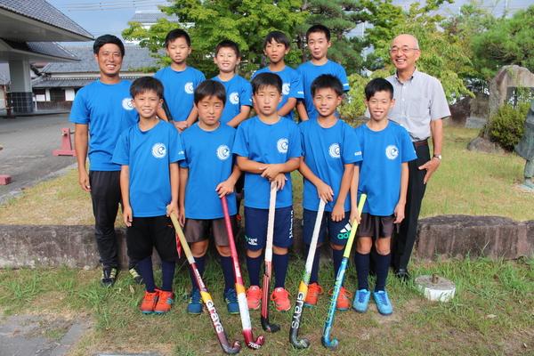 前列はホッケーのスティックを持ち、後列は手を前で組んでいる子供達がおり、市長と笑顔で写っている写真