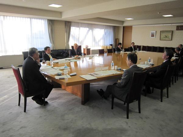 会議室で男性達が椅子に座り、資料を机に広げて会議を行っている写真