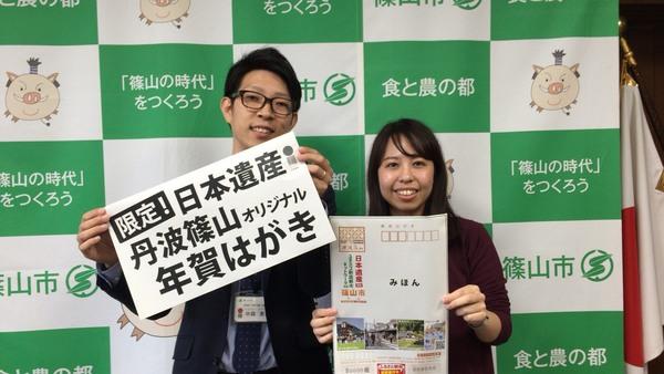 男性が「限定！日本遺産丹波篠山オリジナル年賀はがき」のちらしを持ち、女性が「はがきの見本」を持っている写真