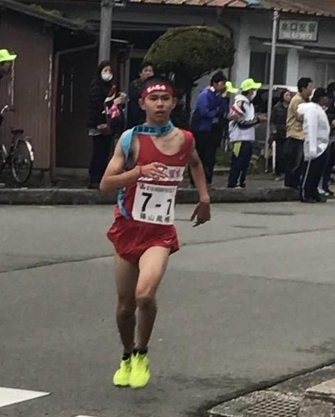 7区アンカーの長尾 健斗君が、たすきをかけて、応援に来ている人達の中を走り抜けている写真