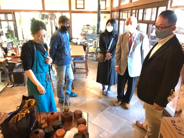 女性の職人が革の作品を市長や関係者に説明している