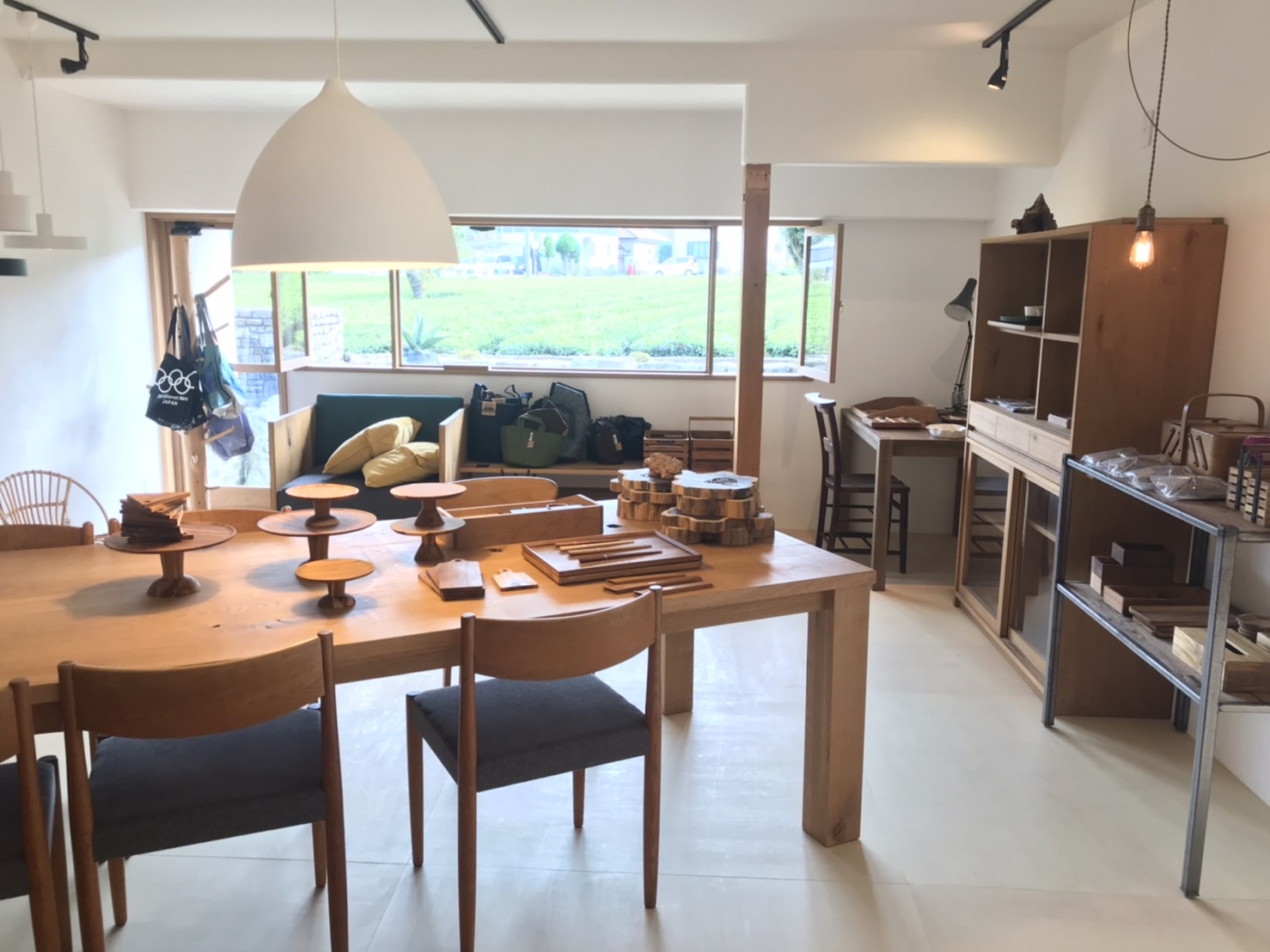 白い壁のギャラリーに木工家具（キッチンテーブル、イス、棚など）が並べられている。