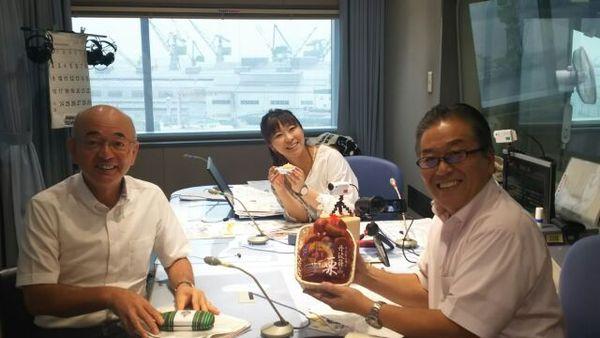 ラジオ局のブースの中で篠山市の栗をもった男性とアシスタントの女性、市長3人が写っている写真