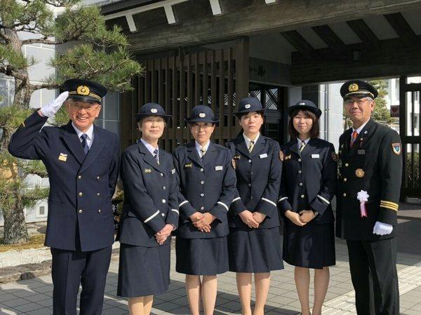 敬礼をしている市長が制服姿の女性消防団員4名らと一緒に記念撮影している写真