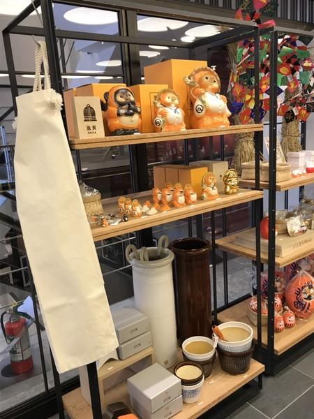 たぬきやだるまの置物などが飾られた棚の写真