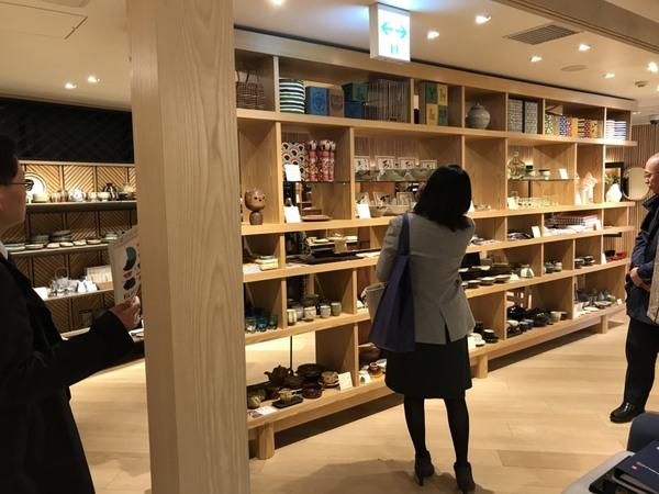 湯飲みや器の陶芸作品、こけしなどが並んでいる棚をみている市長や女性の写真