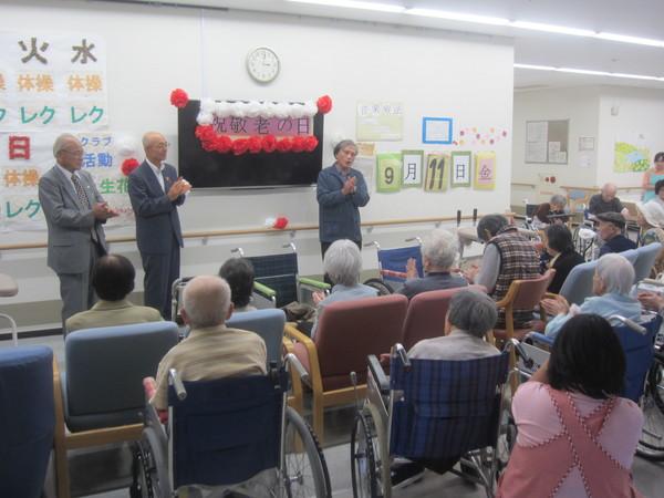 介護施設の敬老会で男性が歌っているのを入所者が鑑賞している写真
