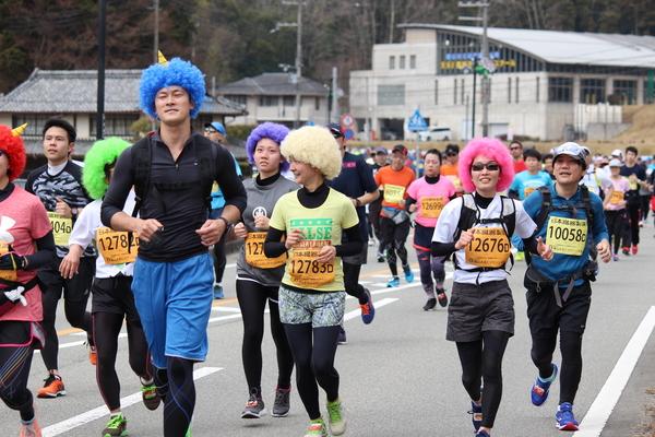 赤、青、ピンク、紫、黄緑、白のアフロのカツラを被ったランナーの写真