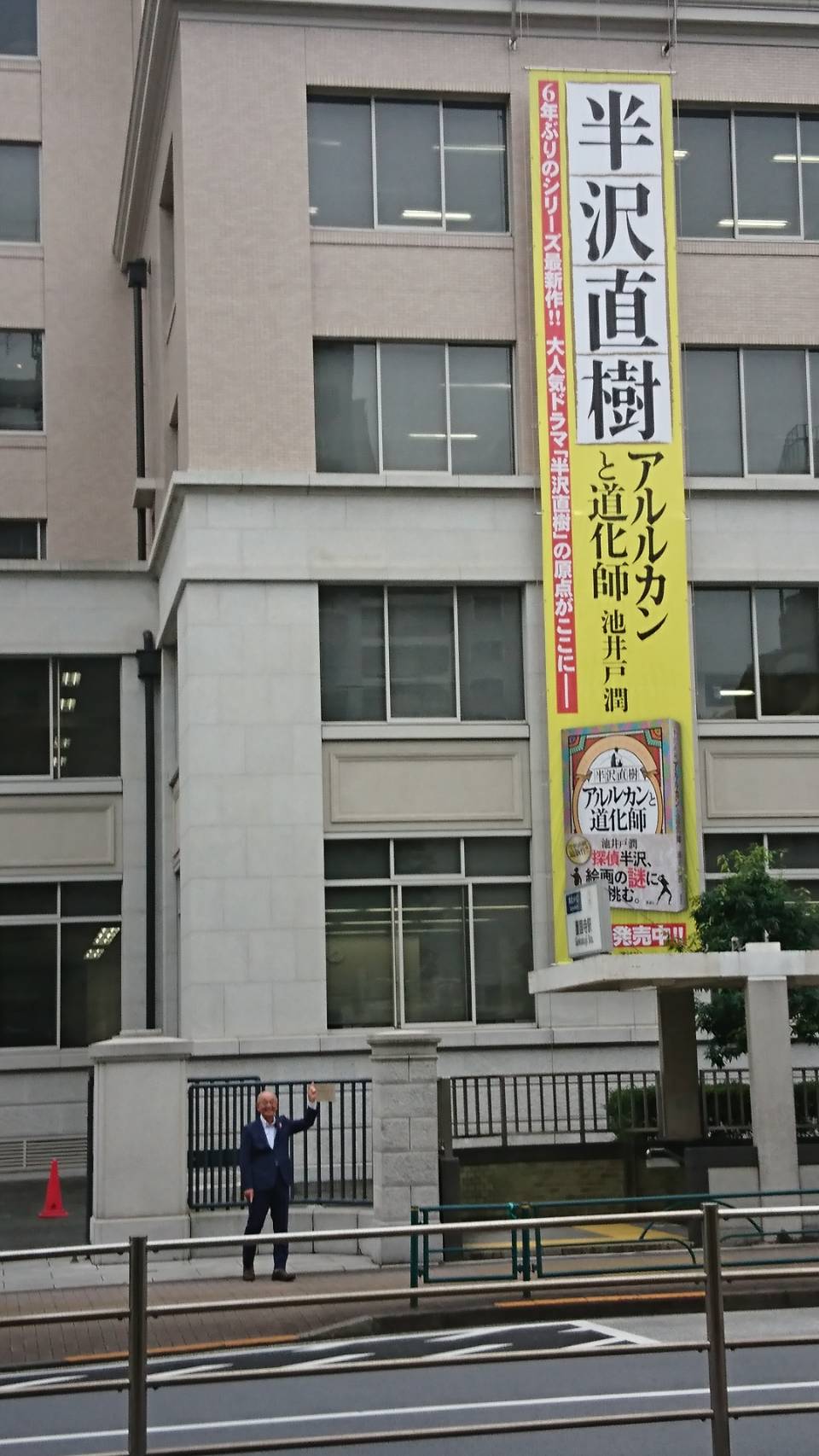 講談社にかかっている懸垂幕を指さす市長