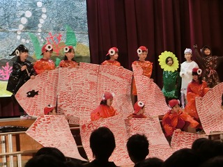 子どもたちがそれぞれ魚のパーツの大きい紙をもって、大きな魚を完成させている写真