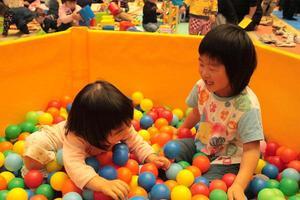 沢山のカラーボールが入っているブースの中で女の子二人がはしゃいで遊んでいる様子の写真