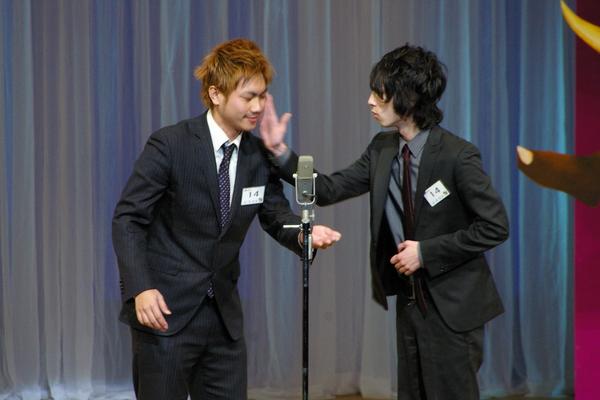 「起（笑）転結」のグループの右側の男性が左側の男性の頬を叩いている、漫才の様子の写真