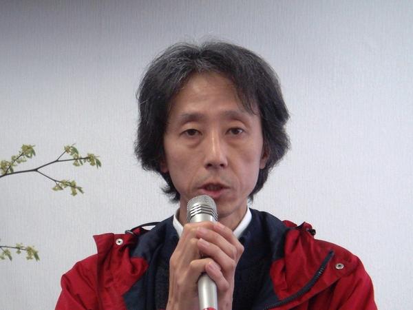 赤いジャンパーを着ており、マイクを持って話をしている織田 信吾さんの写真