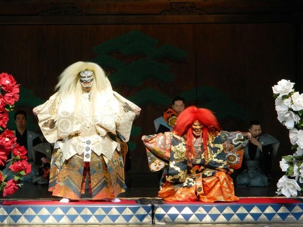 長い白い髪の毛にお面をつけた方が立ち、その隣には長い赤の髪の毛にお面をつけた方が膝をついている写真