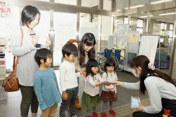 女性が子供達にマスクを配っている写真