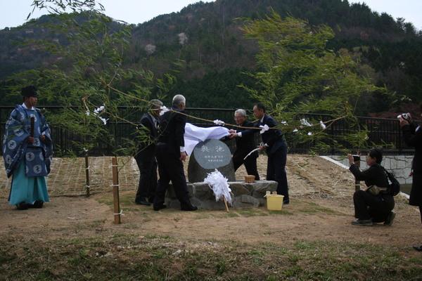 記念碑の上で、白い布を持つ男性4名の写真