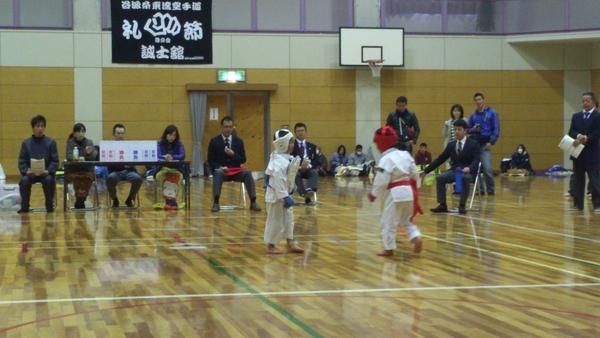 白い防具を頭にかぶっている選手と赤い防具を頭にかぶっている選手が少林寺拳法の試合をしている様子の写真