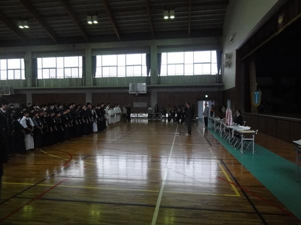 体育館に剣道や空手の篠山城武道大会に参加する選手達が整列しており、前方にはマイクの前に立って話をしてる男性が写っている様子の写真