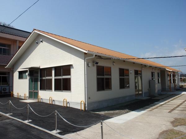 窓がたくさんあり白い壁にオレンジの屋根のあるリハビリ棟を外からとっている写真