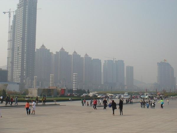広場に人がぽつぽつといて、後ろに超高層ビルが並んでいる写真