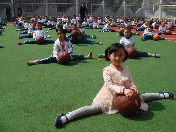 長春路小学校の生徒が並び開脚し、股の間にバスケットボールを置いている写真
