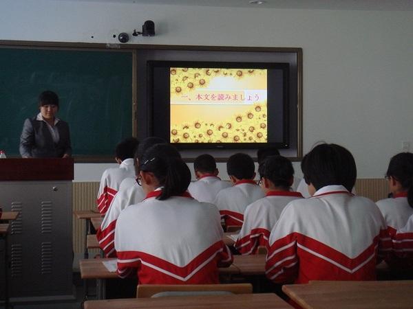 先生が前に立ち、大連市の中学校の生徒が授業の様子を後ろから見た写真