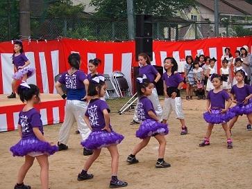 紫の衣装を着た子供達がダンスを披露している写真