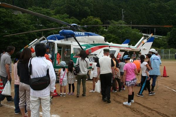 止まっているヘリコプターを子供や大人たちが見ている写真