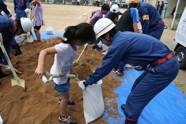 災害対策で子供たちと一緒に土のうを作っている写真