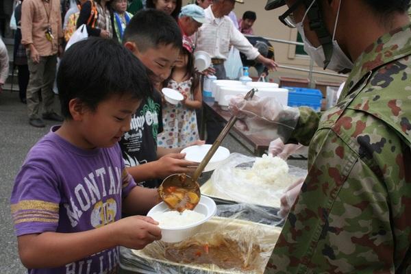 自衛隊の方が並んでいる子供たちにカレーをよそっている写真