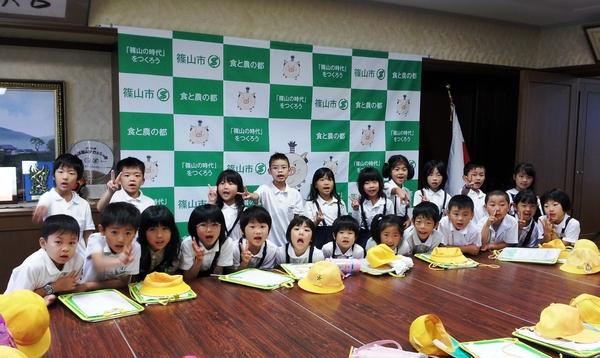 篠山小学校の生徒たちが、机の前でピースサインをしている写真