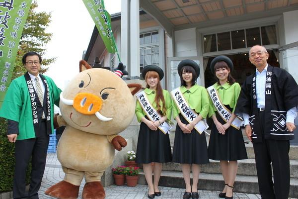 建物の前でキャンペーンレディ3人と男性職員2名とまるいのが並んでいる写真