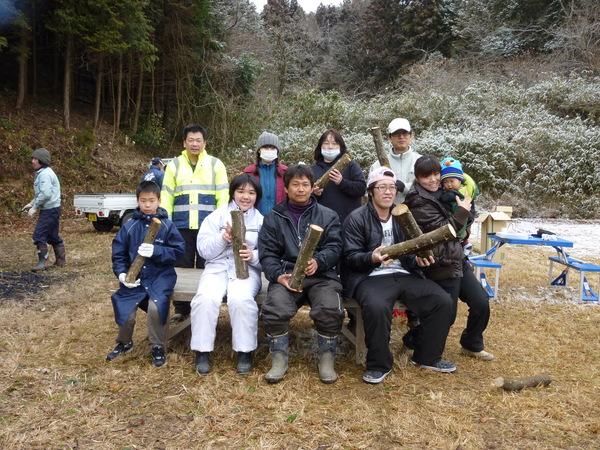 分譲地で家族らが丸太を持って記念撮影している写真