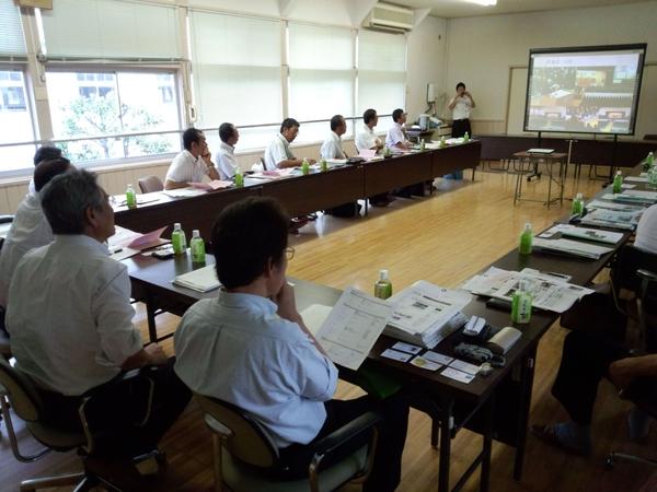 着席している男性が、プロジェクトスクリーンを見ている写真