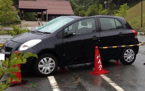 突然の激しい雷雨と突風で車がバイク用の駐車場まで飛ばされ、右側の屋根部分は押し潰されている写真