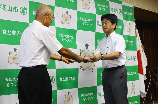 市長が会長の角野 幸博氏へ祝い金を渡している写真
