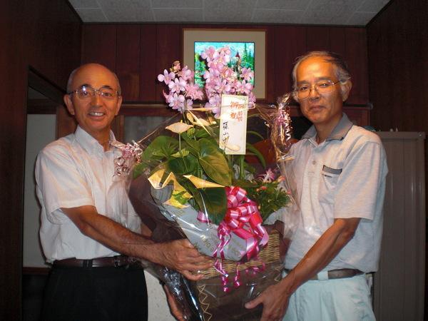 市長が前川 千紗さんの実家でお父さんにピンクの鉢植えをプレゼントしている様子の写真