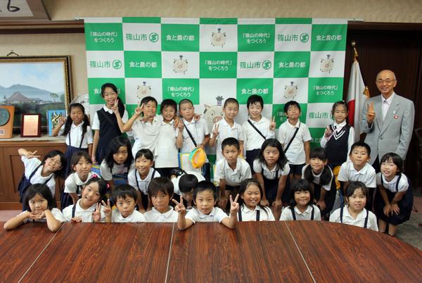 12名の男子児童と14名の女子児童が市長と一緒に笑顔でピースをして記念撮影をしている写真