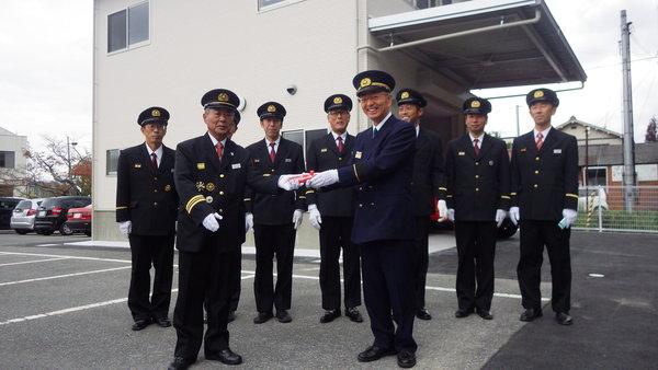 北山団長へ鍵を渡していて、後ろに消防団が7人並び記念撮影をしている写真