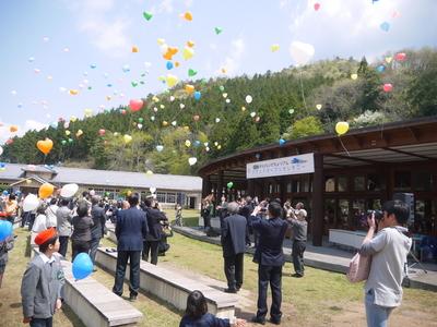 空に舞いあがる色とりどりの風船を見ている人や、写真を撮っている人の写真